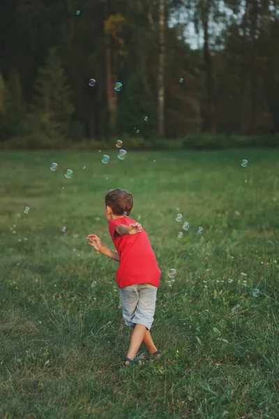 男孩在公园里玩肥皂泡 — 图库照片