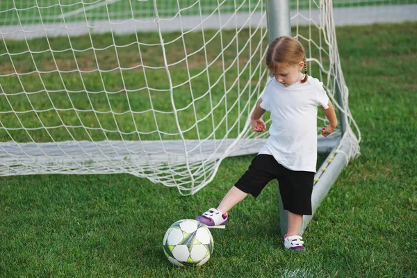 Маленькая счастливая девочка на футбольном поле — стоковое фото