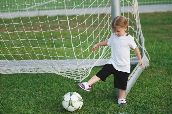 Маленькая счастливая девочка на футбольном поле — стоковое фото