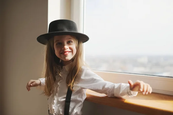 Menina bonito com chapéu preto em casa — Fotografia de Stock