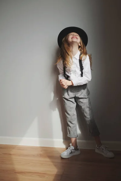 Nettes kleines Mädchen mit schwarzem Hut zu Hause — Stockfoto