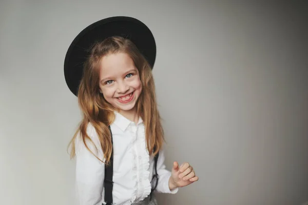 Schattig klein meisje met zwarte hoed thuis — Stockfoto