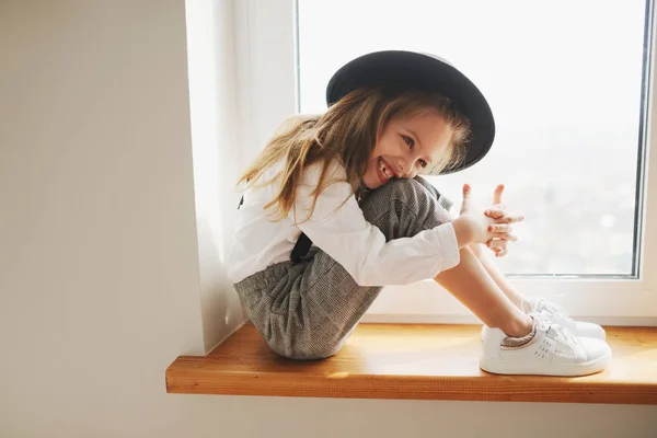 Schattig klein meisje met zwarte hoed thuis — Stockfoto