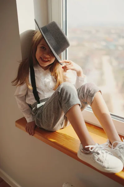 Schattig klein meisje met zwarte hoed thuis — Stockfoto