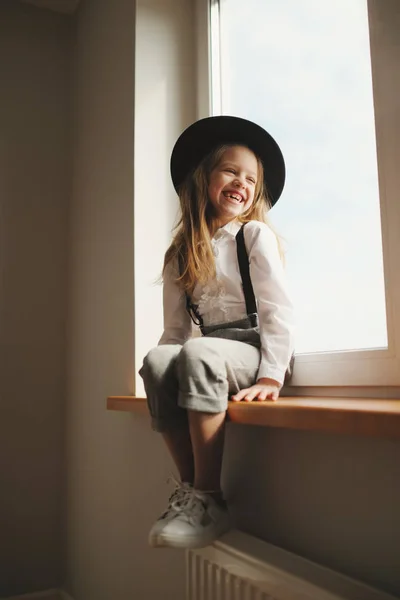 Милая маленькая девочка в черной шляпе дома — стоковое фото
