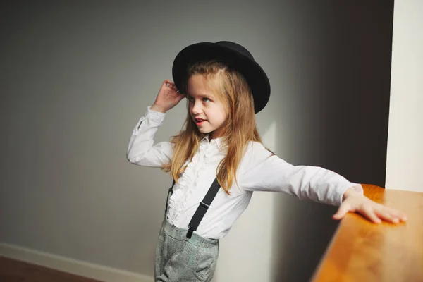 Schattig klein meisje met zwarte hoed thuis — Stockfoto