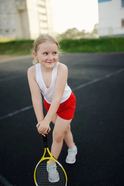 Menina feliz joga tênis no campo ao ar livre — Fotografia de Stock