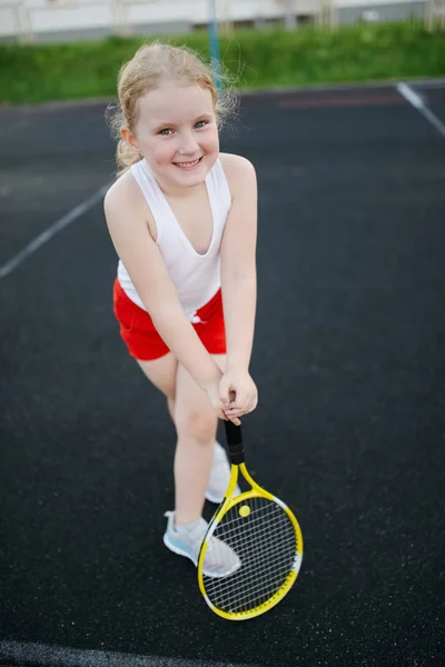 Glad pige spiller tennis på banen udendørs - Stock-foto