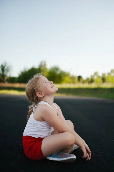 Felice ragazza seduta sul pavimento all'aperto — Foto Stock