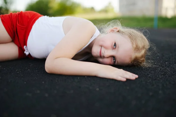 Маленькая девочка лежит на полу на открытом воздухе — стоковое фото