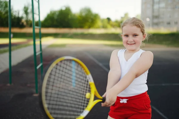 幸せな女の子はコート屋外でテニスを果たしている — ストック写真