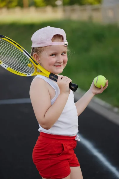 Glad pige spiller tennis på banen udendørs - Stock-foto