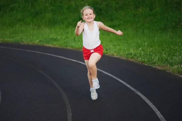 Happy little girl running on the stadium — Stock Photo, Image