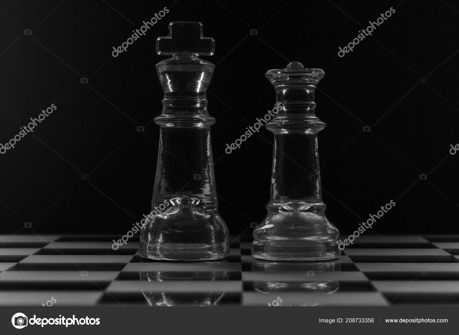 King queen glass chess pieces facing each other black white stock photo