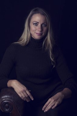 Güzel kadın portre kahverengi deri kanepede oturan düşük ışıkta