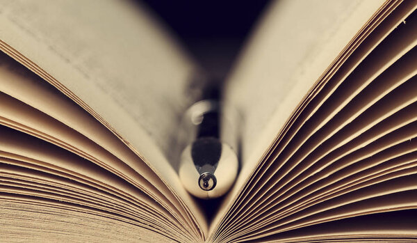 Close-up of a silver pen in the open pages of an old book