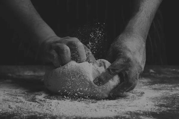 Człowiek z fartuch ręcznie ugniatania kulę ciasta na desce — Zdjęcie stockowe