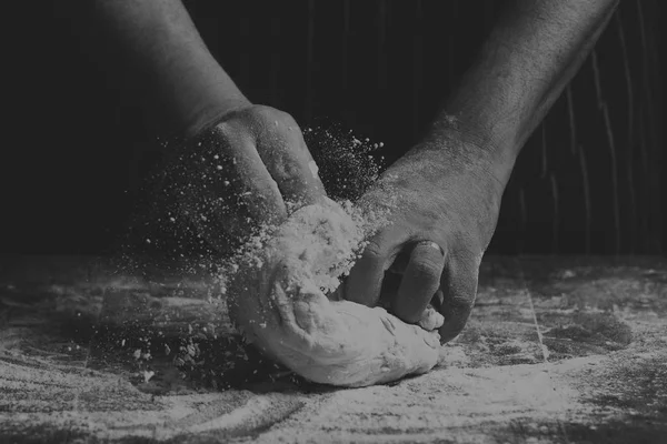 Man with apron kneading a ball of dough on wooden board by hand — Stock Photo, Image