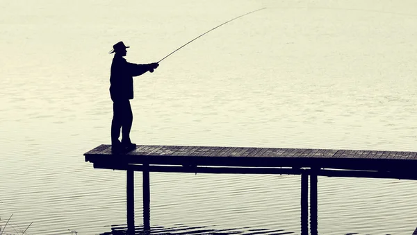 Uomo con attrezzi da pesca a mosca cattura di una trota dal molo su una nebbia — Foto Stock