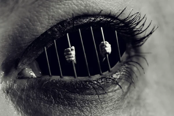 人間の目の中に刑務所の棒を持つ手の概念的なモノクロ写真 — ストック写真