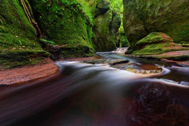 Finnich Glen manzara fotoğrafçılığından akan kırmızı suyu olan küçük bir nehir.