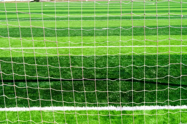 Football net on goal behind back view on field