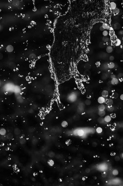 İçinde karanlık bir uçuş, ufuk bokeh su damlaları ile su sıçrama.