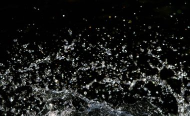 İçinde karanlık bir uçuş, ufuk bokeh su damlaları ile su sıçrama.