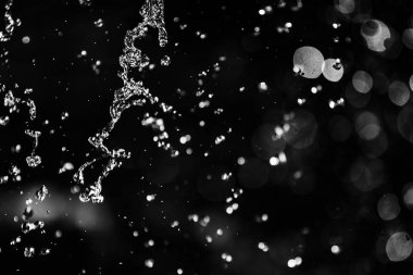 İçinde karanlık bir uçuş, ufuk bokeh su damlaları ile su sıçrama.