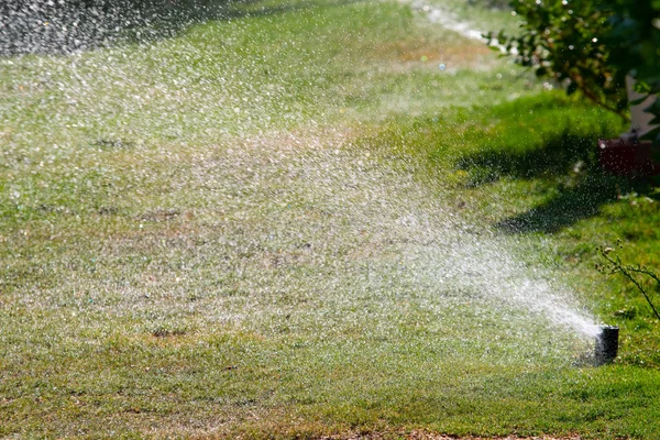 Defocused Irrigation System Watering Green Grass Bokeh Background — Stock Photo, Image