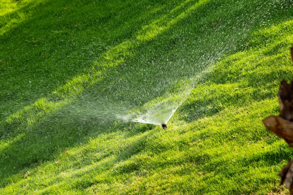 Defocused Irrigation System Watering Green Grass Bokeh Background — Stock Photo, Image