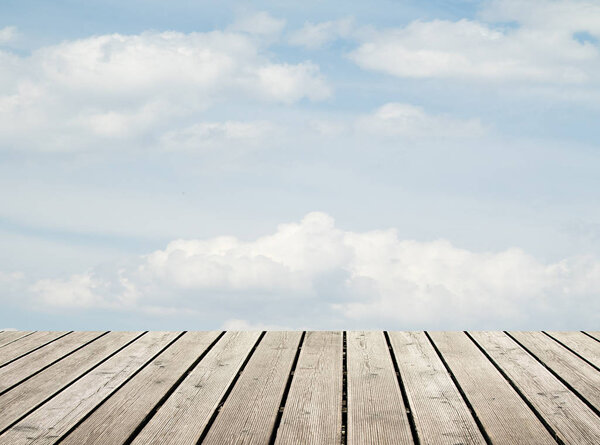 Wooden floor against the sky with clouds