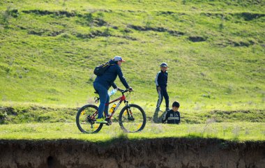 Kazakistan, Çimkent - 23 Nisan 2017. Bozkır yeşil çim bisikletçiler binmek.