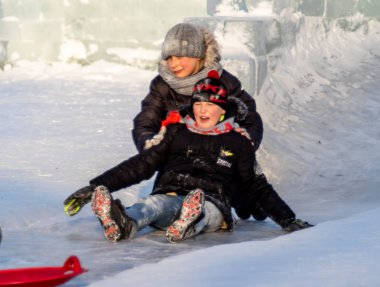 Petropavlovsk, Kazakistan - 8 Ocak 2019: Çocuk buzlu bir tepede binmek. Yetişkinler ve çocuklar parkta birlikte sakin ol.