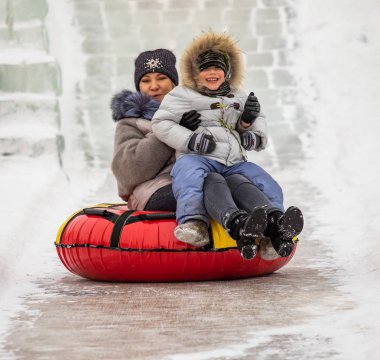 Petropavlovsk, Kazakistan - 13 Ocak 2019: Çocuk buzlu bir tepede binmek. Yetişkinler ve çocuklar parkta birlikte sakin ol.