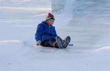 Petropavlovsk, Kazakistan - 8 Ocak 2019: Çocuk buzlu bir tepede binmek. Yetişkinler ve çocuklar parkta birlikte sakin ol.