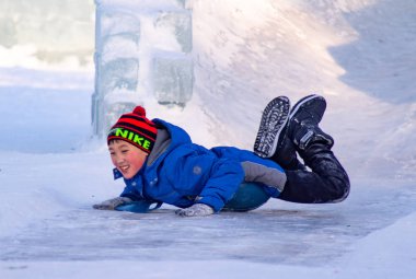 Petropavlovsk, Kazakistan - 8 Ocak 2019: Çocuk buzlu bir tepede binmek. Yetişkinler ve çocuklar parkta birlikte sakin ol.