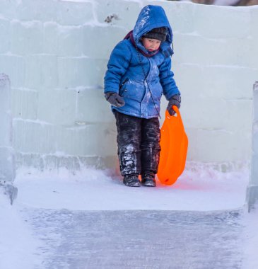 Petropavlovsk, Kazakistan - 8 Ocak 2019: Çocuk buzlu bir tepede binmek. Yetişkinler ve çocuklar parkta birlikte sakin ol.