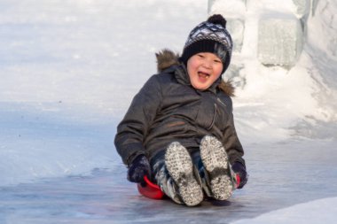 Petropavlovsk, Kazakistan - 8 Ocak 2019: Çocuk buzlu bir tepede binmek. Yetişkinler ve çocuklar parkta birlikte sakin ol.