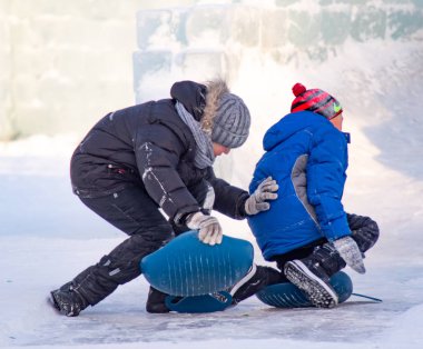 Petropavlovsk, Kazakistan - 8 Ocak 2019: Çocuk buzlu bir tepede binmek. Yetişkinler ve çocuklar parkta birlikte sakin ol.
