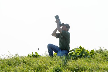 Shymkent, Kazakistan - 04 Mayıs 2017: kamera ile adam manzara vuruyor. Yeşil çimen, beyaz arka plan.