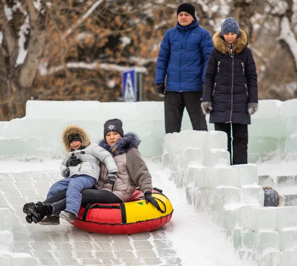 Petropavlovsk, Kazakistan - 13 Ocak 2019: Çocuk buzlu bir tepede binmek. Yetişkinler ve çocuklar parkta birlikte sakin ol.