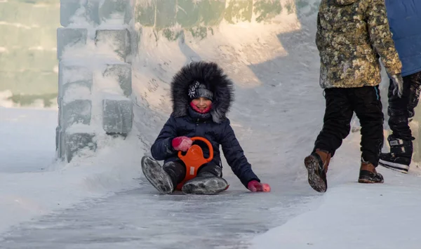 Petropavlovsk, Kazakistan - 8 Ocak 2019: Çocuk buzlu bir tepede binmek. Yetişkinler ve çocuklar parkta birlikte sakin ol.