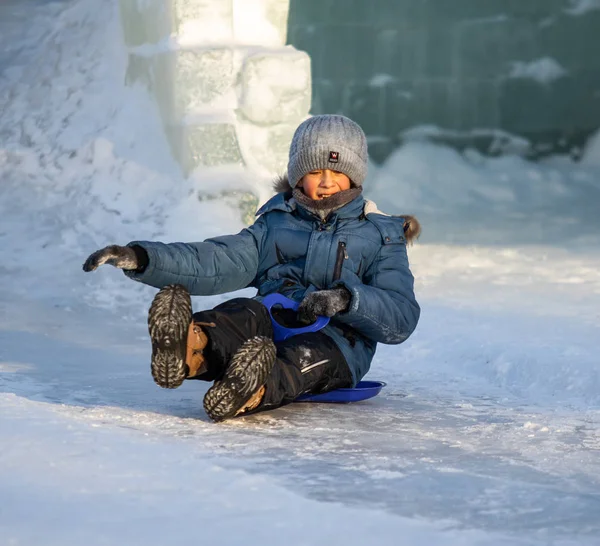 Petropavlovsk, Kazakistan - 9 Ocak 2019: Çocuk buzlu bir tepede binmek. Yetişkinler ve çocuklar parkta birlikte sakin ol.