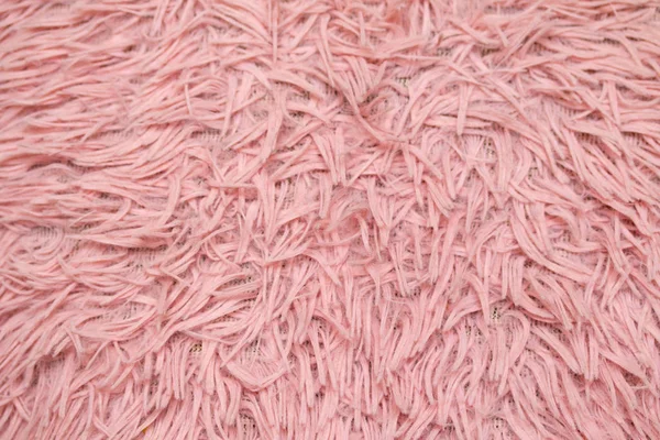 fur rug. Pink natural wool with twists texture background. Cotton wool, white fleece carpet
