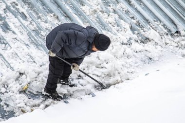Bir adam kaldırır kar küreği üstten görünüm, metal çatı.