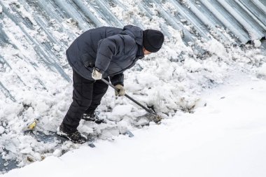 Bir adam kaldırır kar küreği üstten görünüm, metal çatı.