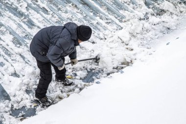 Bir adam kaldırır kar küreği üstten görünüm, metal çatı.