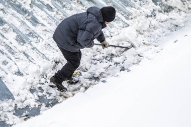 Bir adam kaldırır kar küreği üstten görünüm, metal çatı.