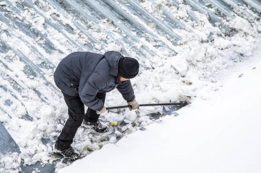 Bir adam kaldırır kar küreği üstten görünüm, metal çatı.
